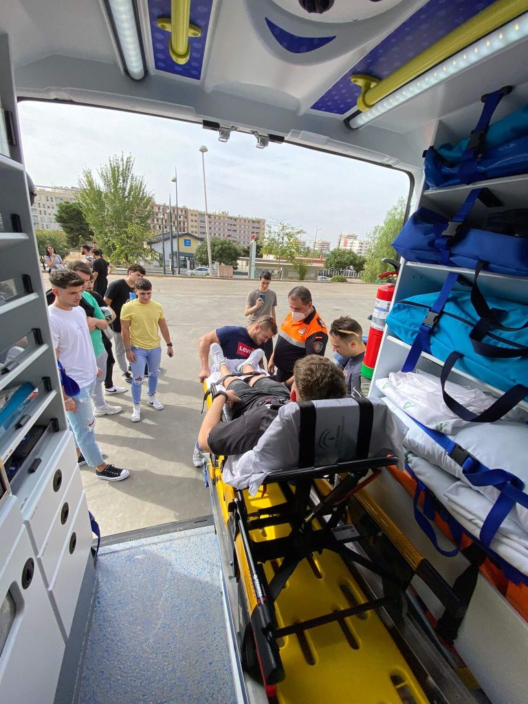 Alumnado de CETES del grado medio de Técnico en Emergencias Sanitarias practicando subida de camilla en ambulancia en la nave de ambulancias